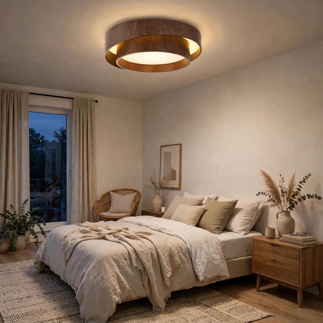 A brown woodgrain flush mount light glows above a bed with cream bedding, wooden bedside furniture, and a woven chair.