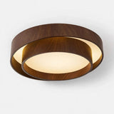 A modern circular flush-mount ceiling light fixture with a dark brown wood-grain outer ring and a warm white frosted glass inner disc, shown against a plain light gray background.