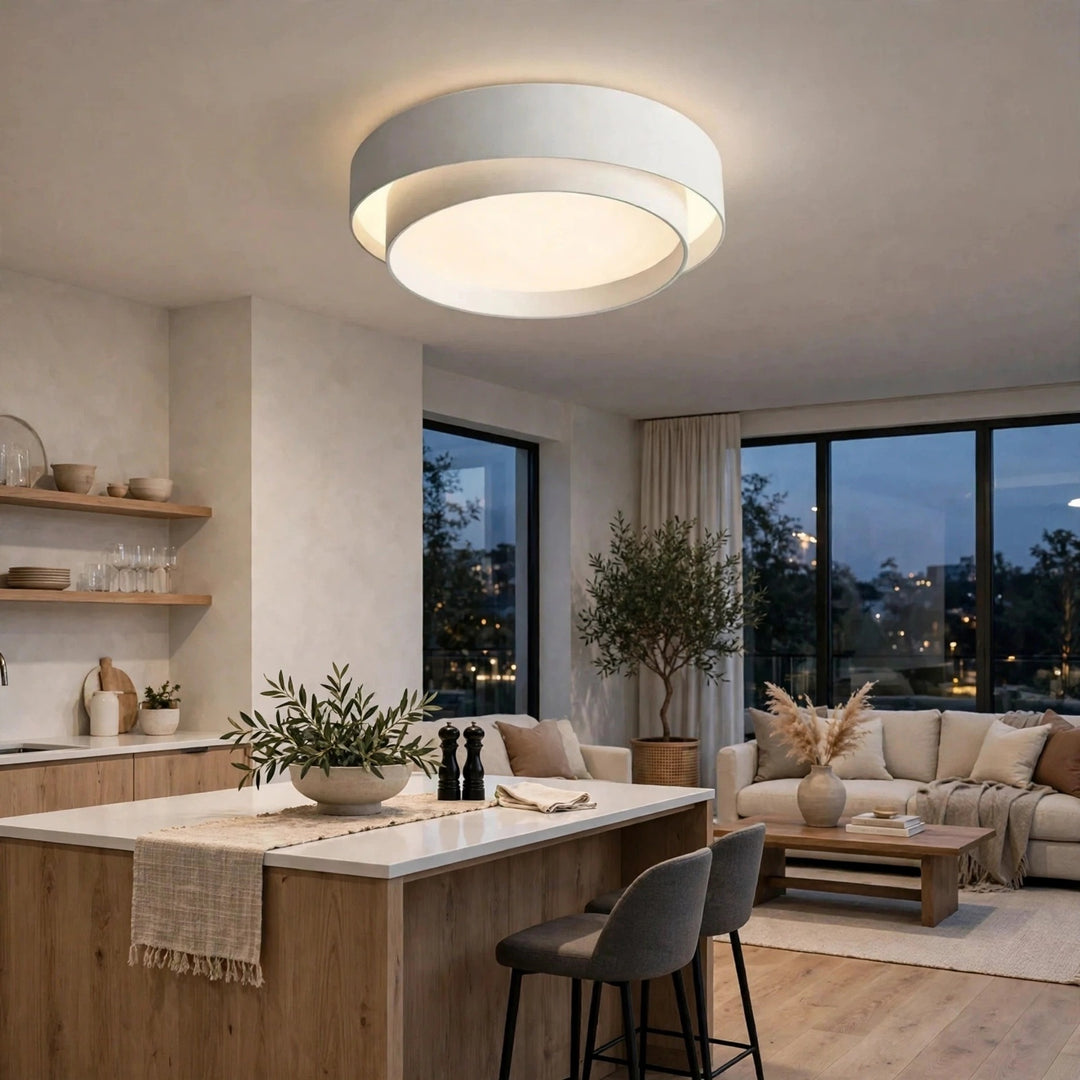 A modern double-ring flush mount ceiling light with a white outer ring and a warm white inner ring, glowing in a contemporary kitchen and living room setting.