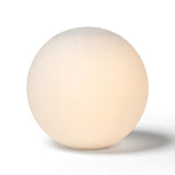 White glass globe wall sconce glows softly against a plain white background, casting a shadow to the right.