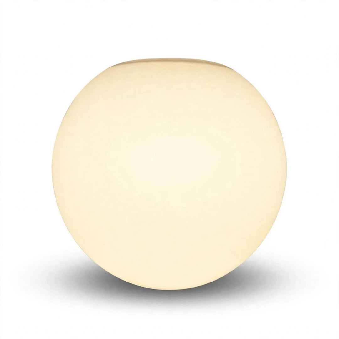 White glass globe wall sconce appears warm cream against a white background, with a soft gray shadow beneath.
