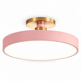 A modern semi-flush mount ceiling light featuring a wide pink cylindrical shade, a white diffuser inside, and a brushed gold metal ceiling mount and central collar.