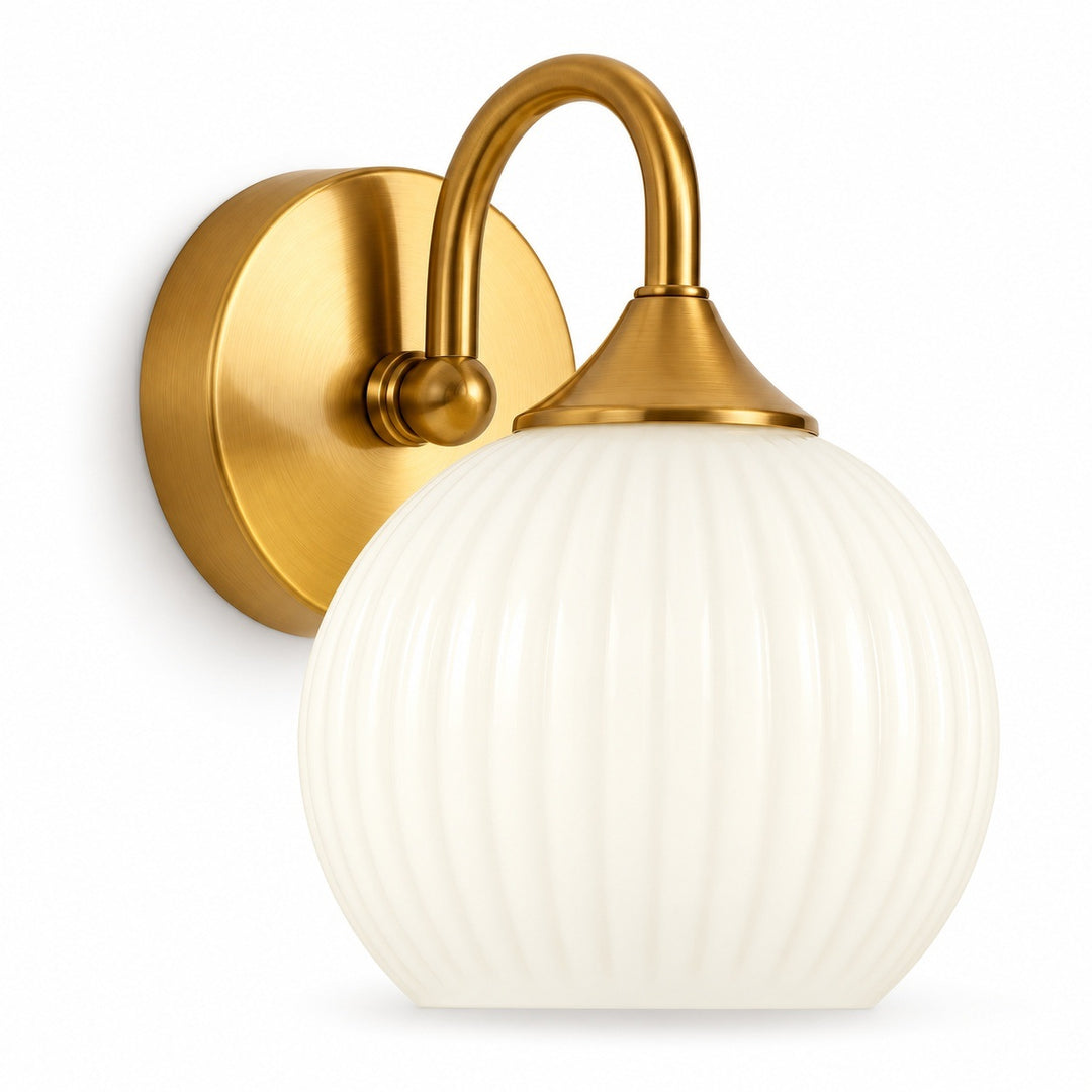 A wall-mounted sconce light fixture with a round white ribbed glass shade and a brushed gold metal wall plate and curved arm, shown against a plain white background.