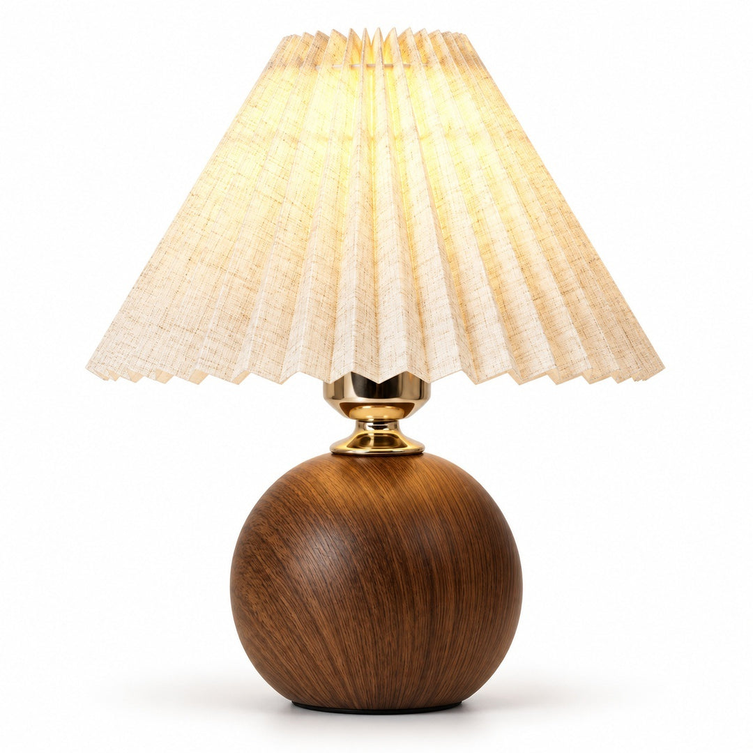 A table lamp with a spherical dark brown wooden base, a gold-finished neck, and a pleated beige fabric shade glowing with warm light, set against a plain white background.