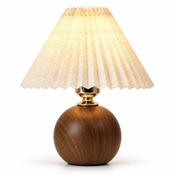 A table lamp with a spherical dark brown wooden base, a gold-finished neck, and a pleated beige fabric shade glowing with warm light, set against a plain white background.