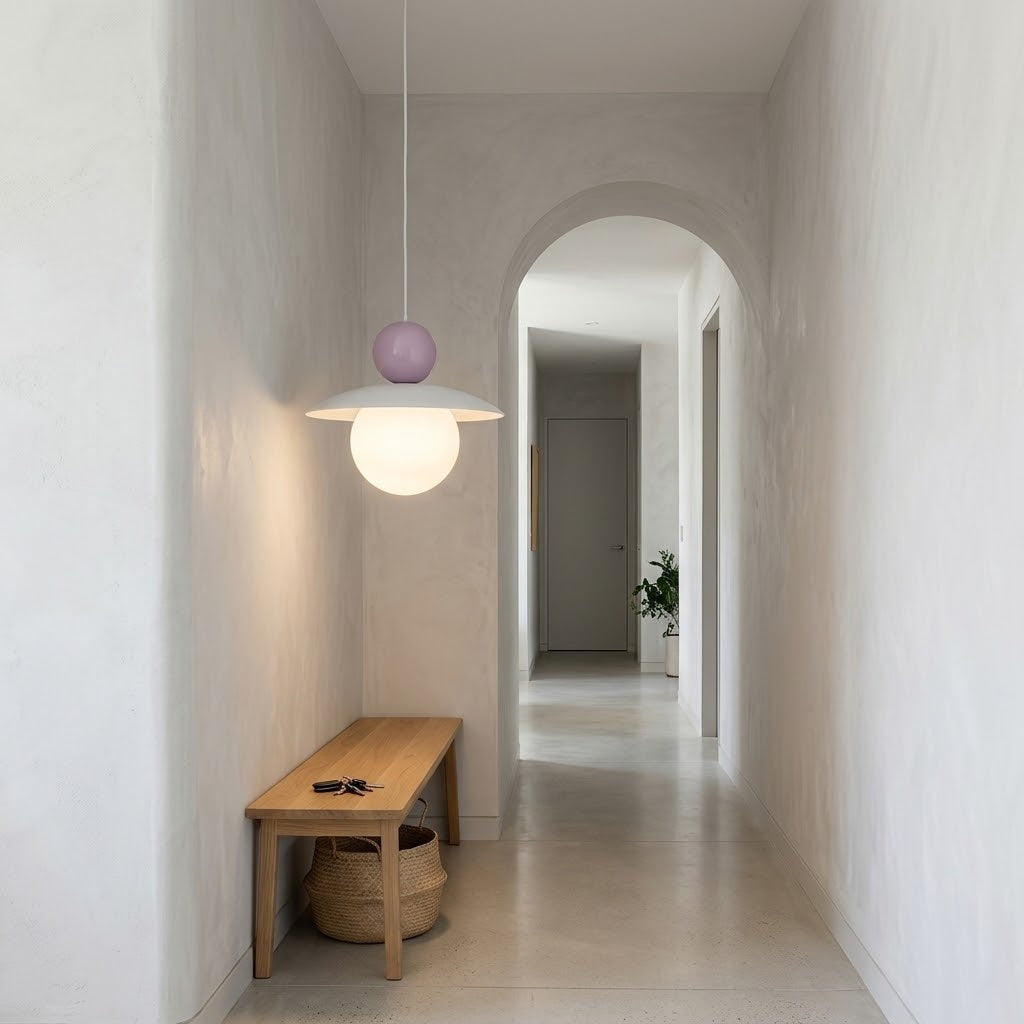 A modern pendant light with a white conical shade and two spherical bulbs, one white and one lavender purple, hanging in a minimalist hallway with a wooden bench.