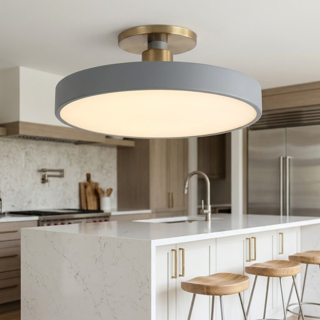 A modern semi-flush mount ceiling light fixture with a matte gray outer shade and a warm white illuminated diffuser, suspended from a brushed brass ceiling mount in a contemporary kitchen setting.