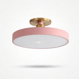 A modern semi-flush mount ceiling light with a circular pink shade, a white diffuser, and a brushed gold metal ceiling mount, shown against a plain white background with a soft shadow underneath.