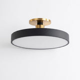 A modern semi-flush mount ceiling light fixture with a matte black circular shade, a white diffuser panel, and brushed gold metal mounting hardware, shown against a plain white background.