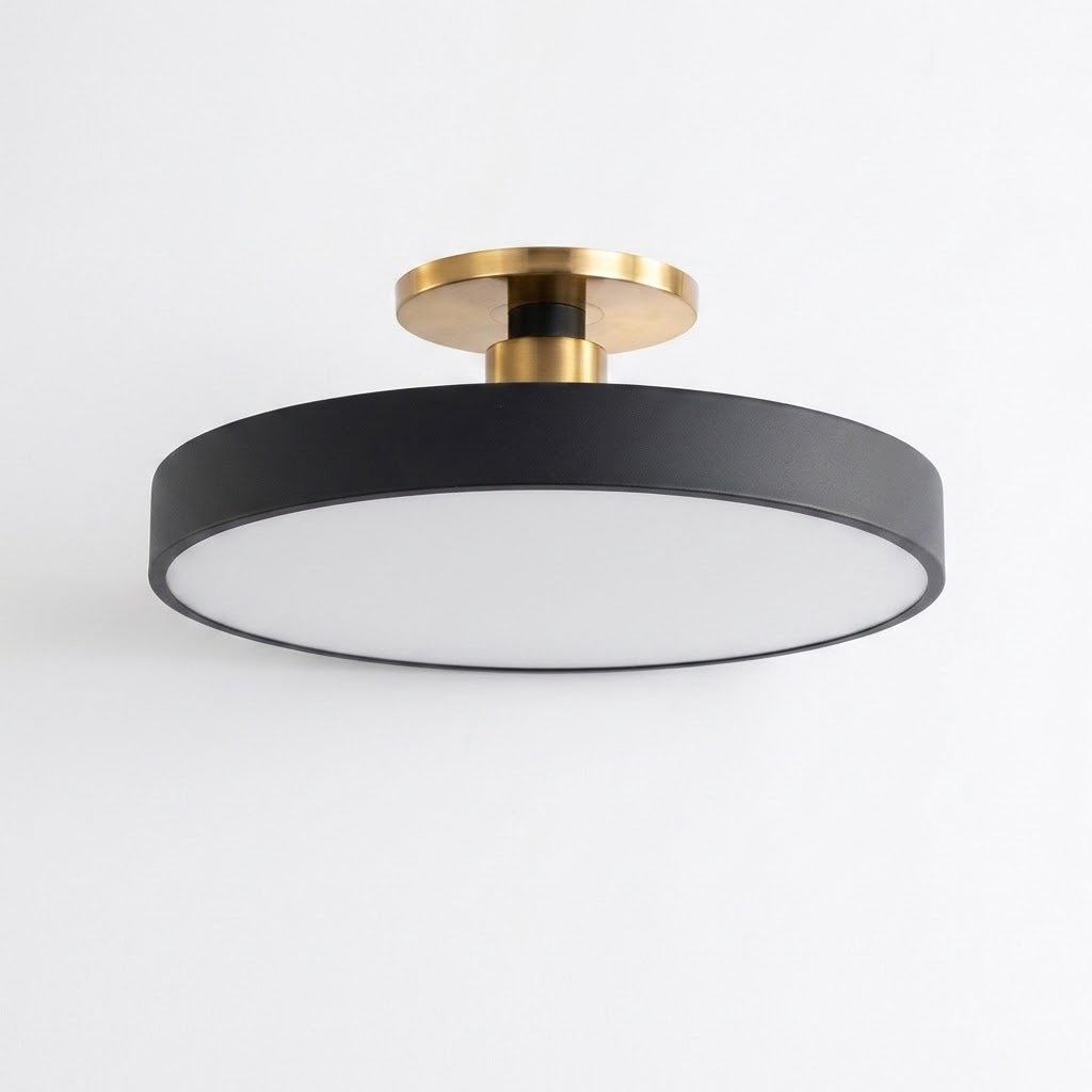 A modern semi-flush mount ceiling light fixture with a matte black circular shade, a white diffuser panel, and brushed gold metal mounting hardware, shown against a plain white background.