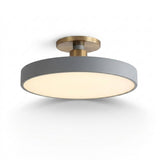 A modern semi-flush mount ceiling light fixture with a matte gray cylindrical shade and a brushed brass metal ceiling mount, shown against a plain white background.