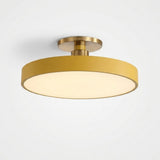 A modern semi-flush mount ceiling light fixture with a matte gold cylindrical shade and a warm white illuminated diffuser, shown against a plain white background.