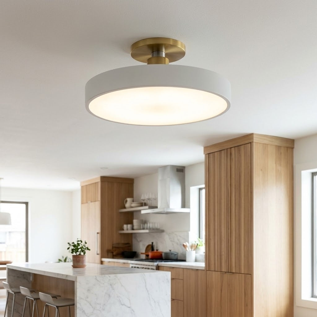 A modern semi-flush mount ceiling light with a white cylindrical shade and a brushed gold circular ceiling canopy, installed in a bright contemporary kitchen.
