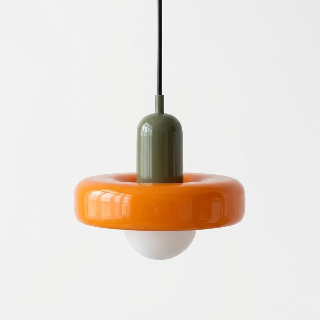 A modern pendant light with a glossy orange ring-shaped shade, an olive green cylindrical neck, and a white globe bulb, suspended by a black cord against a plain white background.
