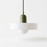 A modern pendant light with a wide white flared shade, a glossy olive green central column, and a black hanging cord, shown against a clean white background.