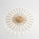 Gold metal ceiling light with a circular center and layered starburst rods ending in glowing white tips against a white background.