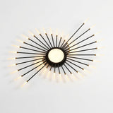 Black metal ceiling light viewed at an angle against white, with a glowing circular center and radiating illuminated rods.