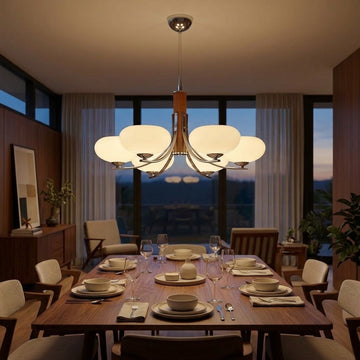 A modern multi-light chandelier with six glowing frosted glass shades hangs over a wooden dining table set for six in a warmly lit contemporary dining room.