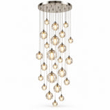 A modern multi-light chandelier with a brushed nickel circular canopy and multiple clear glass spherical bulbs of varying sizes hanging at different intervals against a plain white background.