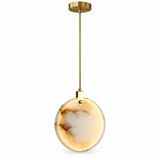 A chandelier features a glowing cream marble disc with dark amber veining, a gold stem, and a round canopy against white.