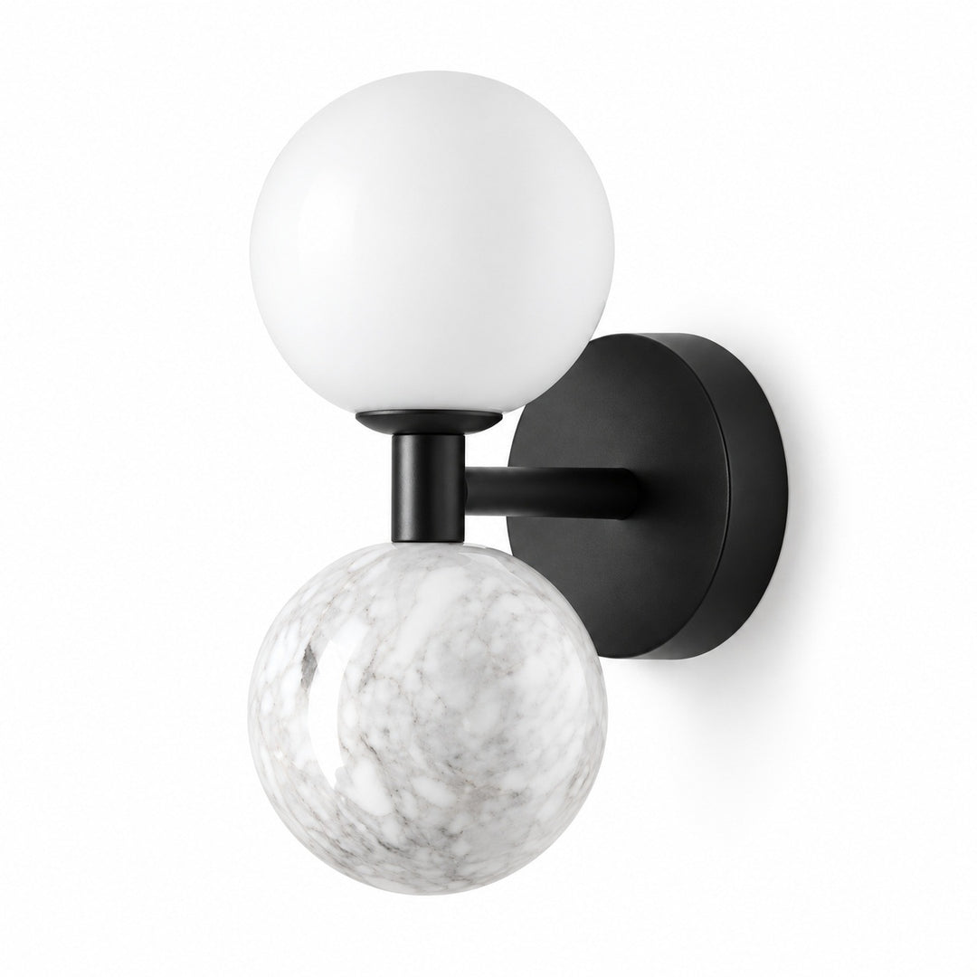 A modern wall-mounted sconce with a matte black circular backplate, horizontal arm, and vertical stem, featuring one matte white spherical globe and one white-and-gray marbled globe, shown on a plain white background.