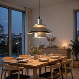 A modern two-tier pendant light with a brushed silver metal finish and warm glowing bulbs, hanging over a wooden dining table in a stylishly decorated dining room.
