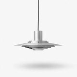 A modern silver pendant light with a layered, disc-like shade suspended by a thin black cord against a clean white background.