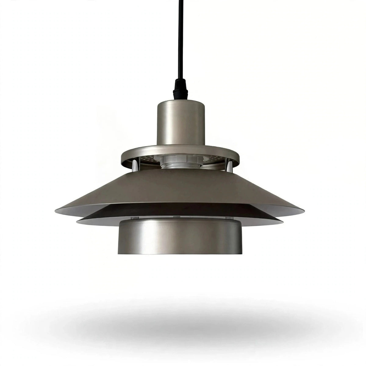 A modern pendant light fixture with a brushed metal finish, featuring a wide conical shade and a black hanging cord, shown against a plain white background.