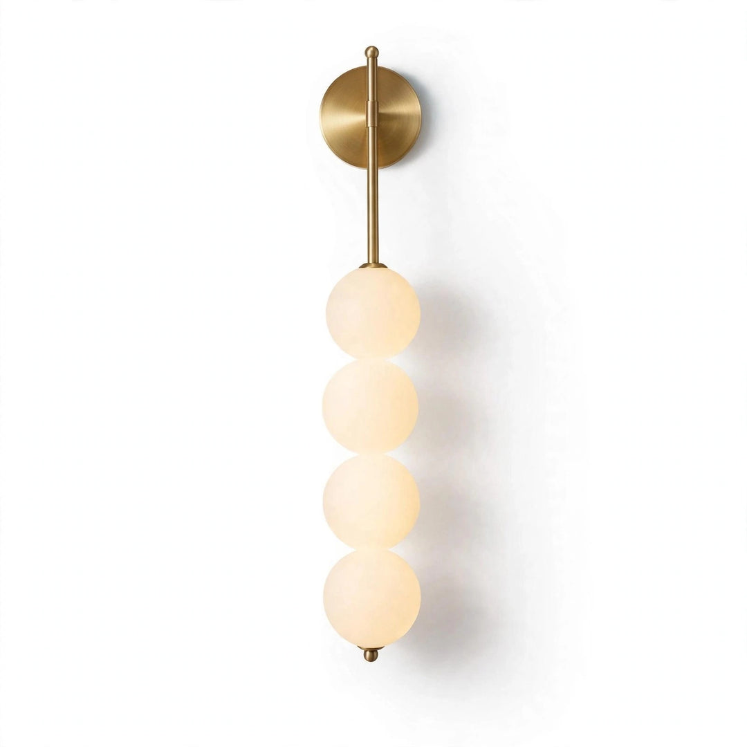 A modern wall sconce light fixture featuring a vertical brass rod with four stacked frosted glass beads, mounted on a plain white wall.