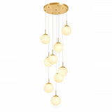 A modern multi-light pendant chandelier with a gold circular ceiling canopy and nine glowing frosted glass globe shades of varying sizes, suspended by thin cables against a plain white background.