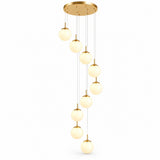 A modern multi-light linear pendant chandelier with a brushed gold circular ceiling canopy, multiple thin suspension wires, and nine glowing frosted glass globe shades arranged in a staggered vertical line.