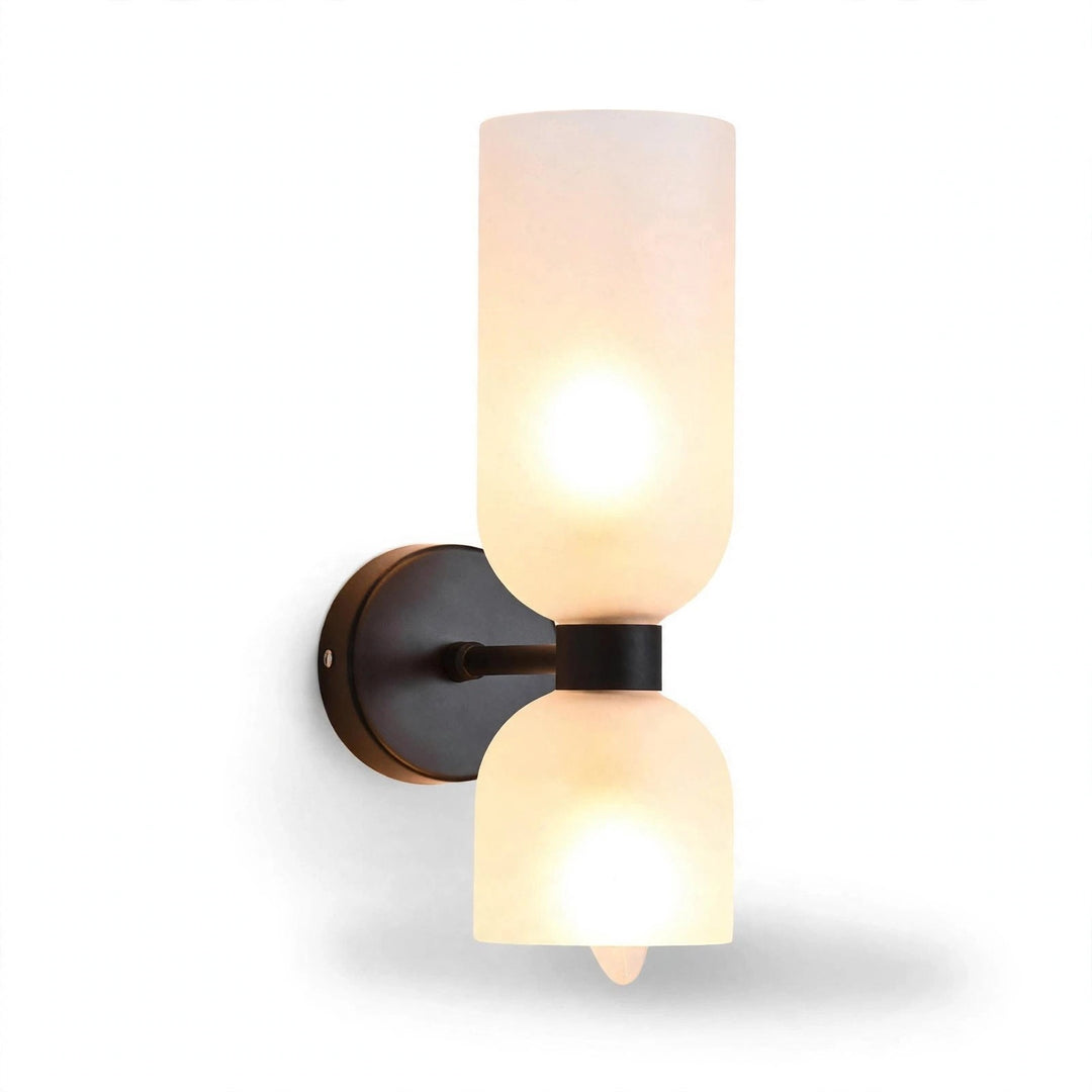 A modern wall-mounted sconce light fixture with two frosted glass shades, one cylindrical and one bell-shaped, set against a plain white background.