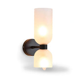 A modern wall-mounted sconce light fixture with two frosted glass shades, one cylindrical and one bell-shaped, set against a plain white background.