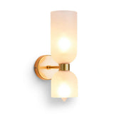 A modern double-shade wall sconce with frosted glass shades and a brushed gold metal base, shown illuminated against a plain white background.