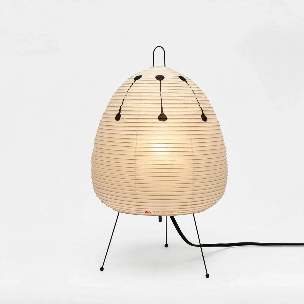 A modern table lamp with a ribbed, egg-shaped beige shade supported by three thin black metal legs, shown against a plain white background.