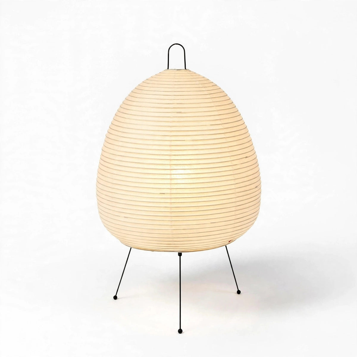 A modern table lamp with a ribbed, egg-shaped beige paper shade on a black metal tripod base, photographed against a clean white background.