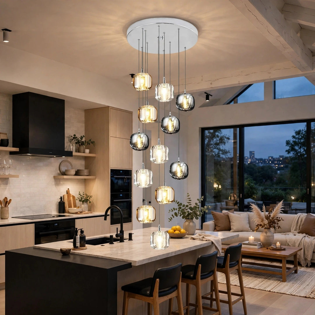 A modern multi-light pendant chandelier with clear glass cylindrical and spherical shades hanging over a kitchen island in a contemporary home interior.