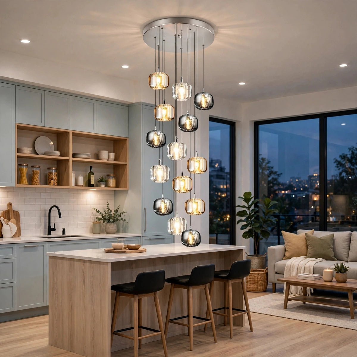 A modern multi-light pendant chandelier with clear glass spherical shades and warm glowing bulbs, hanging over a kitchen island in a stylishly decorated kitchen and living room.