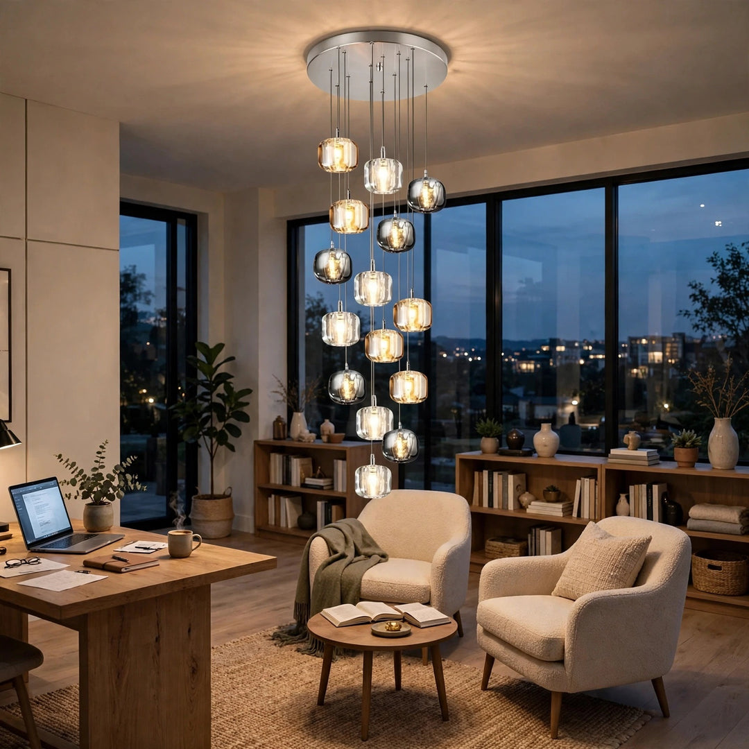 A modern multi-light chandelier with clear glass spherical shades and a brushed silver metal frame hangs in a stylishly furnished home office at dusk.
