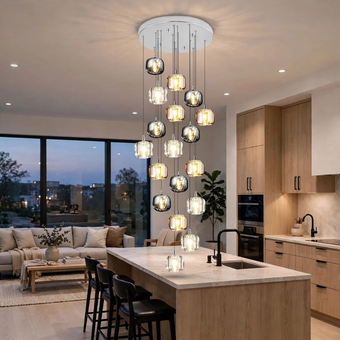A modern multi-light pendant chandelier with clear glass spherical shades and warm white bulbs, hanging over a kitchen island in a bright, contemporary apartment interior.