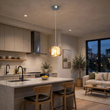 A single-light amber crystal chandelier hangs above a marble kitchen island, with wooden stools and a cream sofa nearby.