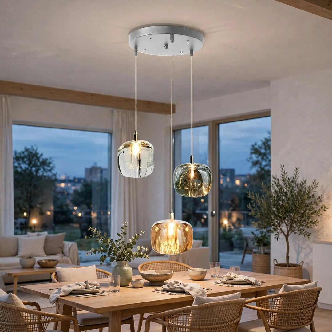 Three-light chandelier with clear, smoky, and amber crystal shades hangs above a wooden dining table surrounded by woven chairs.