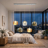 A five-light linear chandelier with amber, clear, and smoky crystal shades hangs above a cream bed beside corner windows.