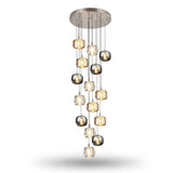 A fifteen-light chandelier has clear, amber, and smoky grey crystal shades staggered beneath a round silver canopy against a white background.