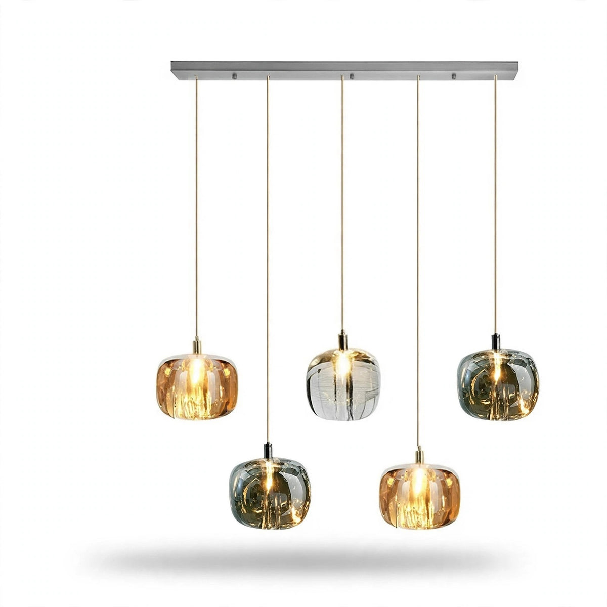 A linear chandelier has five illuminated amber, clear, and smoky grey shades at alternating heights beneath a rectangular silver canopy against white.