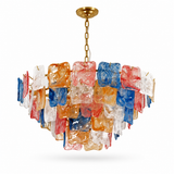 A modern chandelier with a gold-toned chain and ceiling canopy, featuring multiple translucent square glass shades in red, blue, orange, and clear, arranged in a tiered circular structure against a white background.