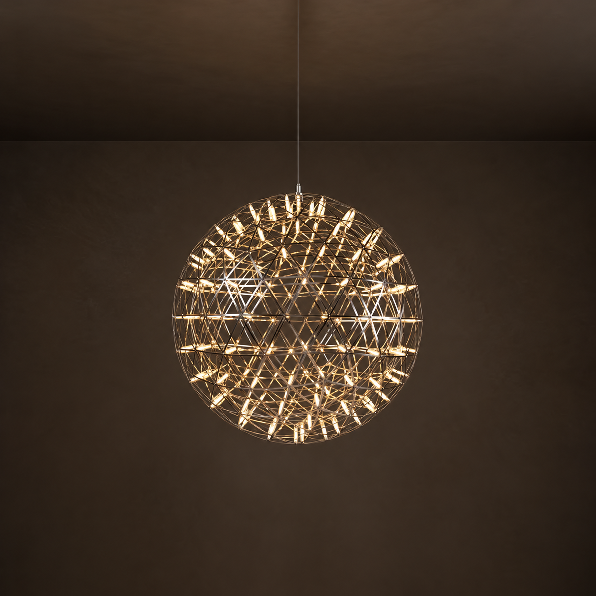 Spherical pendant light with a reflective metal lattice and glowing tubes hangs from a thin cable against a dark brown background.