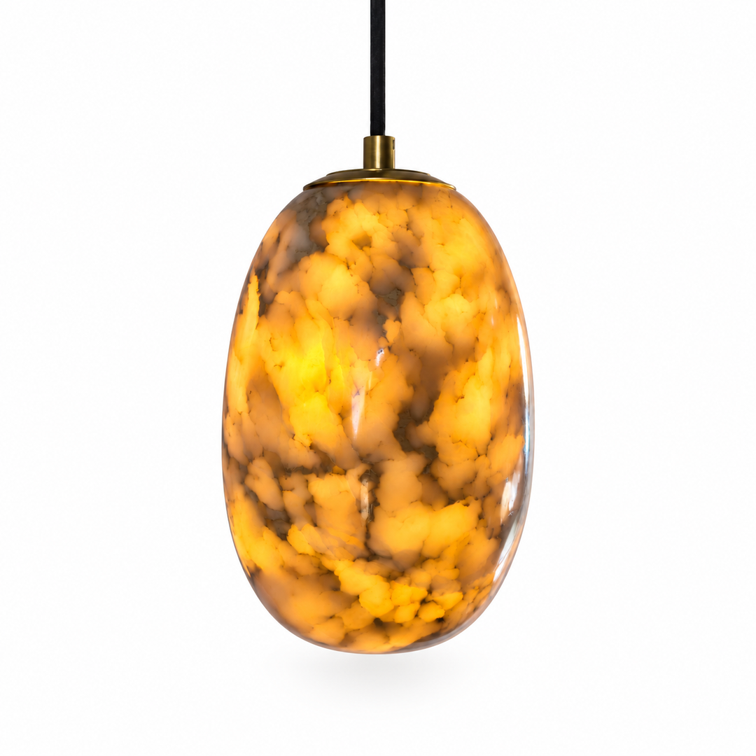 An oval pendant light with a glossy, marbled amber and gold glass shade, suspended by a black cord with a brass top cap, set against a plain white background.