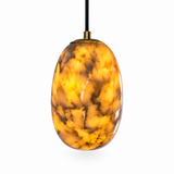 An oval pendant light with a glossy, marbled amber and gold glass shade, suspended by a black cord with a brass top cap, set against a plain white background.