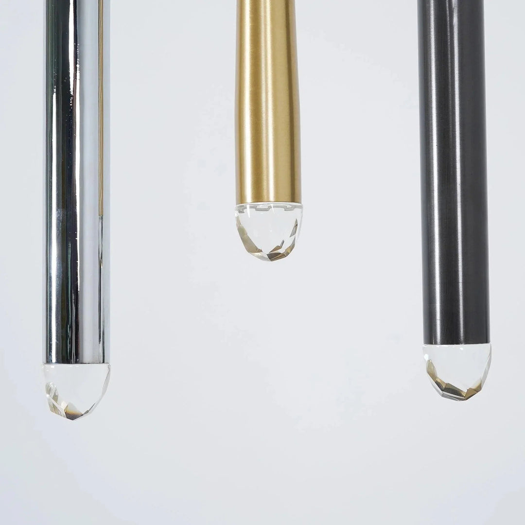 Chandelier detail showing silver, brass, and black tubes with clear faceted crystal tips against a pale background.
